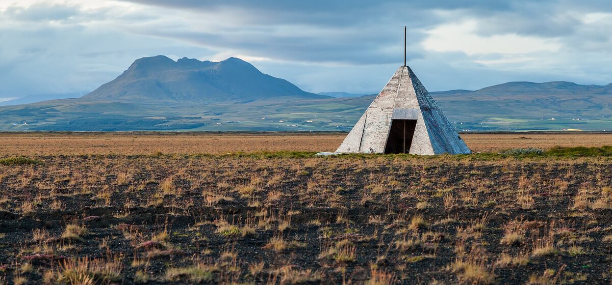 Pyramid-shaped plywood hut on a dark Icelandic moor at dusk